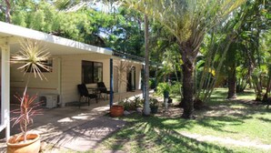 A covered outdoor area with a patio, seating, and potted plants. - Seaward Cottage, Nelly Bay (NELLY BAY)