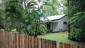 A single-story house with a covered porch, surrounded by dense tropical vegetation. - Seaward Cottage, Nelly Bay (NELLY BAY)