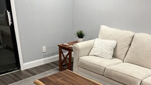 A living room with a wooden coffee table, a beige sofa, and a small side table with a plant. - Wake up to the sunrise over the Atlantic! Beautiful ocean views from balcony  (North Myrtle Beach)