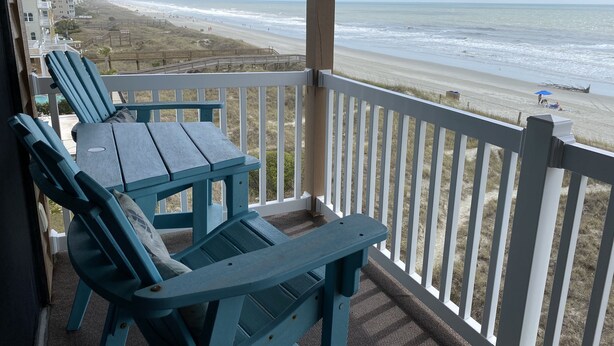 A balcony with blue Adirondack chairs and a view of the beach and ocean. - Wake up to the sunrise over the Atlantic! Beautiful ocean views from balcony  (North Myrtle Beach)