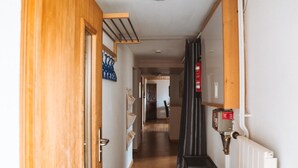 A hallway with a wooden door, a radiator, and a fire extinguisher. - Burkhalter by Interhome (Zweisimmen)