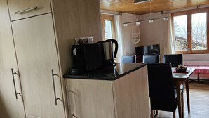 A modern kitchen with wooden cabinets and a black countertop. There is a coffee maker and a kettle on the counter. - Burkhalter by Interhome (Zweisimmen)