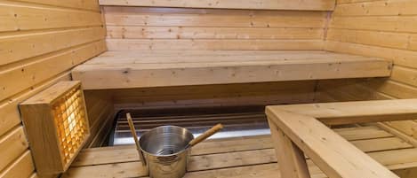 Una sauna con bancos de madera y un cubo de metal.