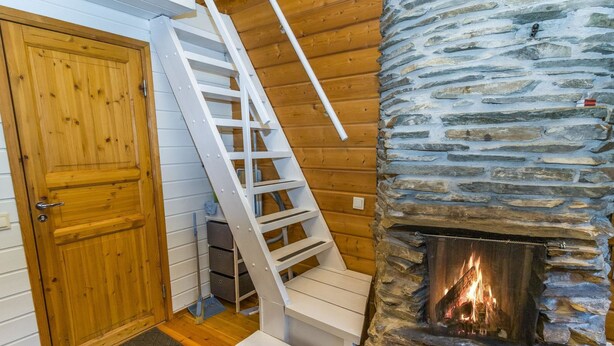 Un intérieur en bois avec une cheminée en pierre, une porte en bois et un escalier blanc.