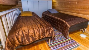 Une petite pièce chaleureuse, avec deux lits, des murs en bois et un plafond en pente.
