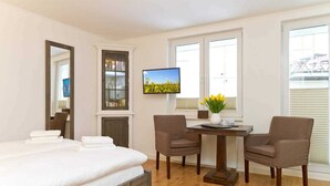 Ein Hotelzimmer mit einem Bett, einem Schreibtisch, zwei Stühlen, einem Fernseher und einem Bücherregal.