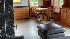 A wooden cabin interior with a dining area, kitchen, and seating area. - Brunnquell by Interhome (Bettmeralp)