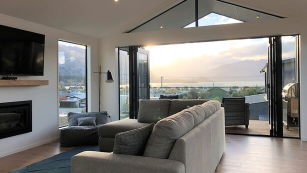 A modern living room with a large window, a flat-screen TV, and a fireplace.