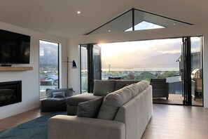 A modern living room with a large window, a flat-screen TV, and a fireplace.