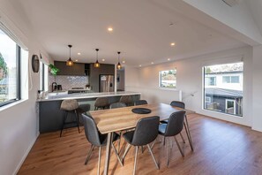A modern kitchen with a central island, wooden dining table, and chairs.