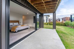 A modern bedroom with a large bed, a wooden ceiling, and a view of a snowy mountain landscape.