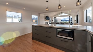 A modern kitchen with a large island, built-in oven, and pendant lighting.