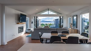 A modern interior with a dining area, sofa, and large windows offering a mountain view.