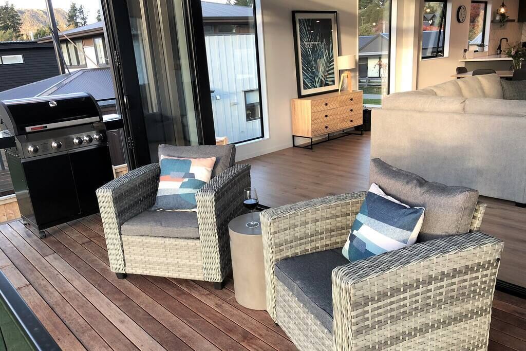 Un espace de vie extérieur accueillant, avec des meubles en osier, un barbecue et une vue sur le jardin.