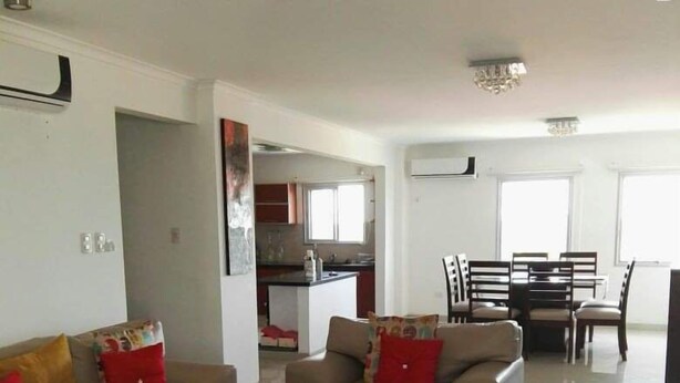 A modern living room with a sofa, coffee table, and a dining area with chairs and a table. - Santa Cruz Furnished Department (Santa Cruz)