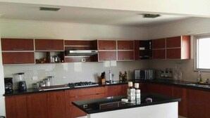 A modern kitchen with a central island, wooden cabinets, and a large window providing natural light. - Santa Cruz Furnished Department (Santa Cruz)