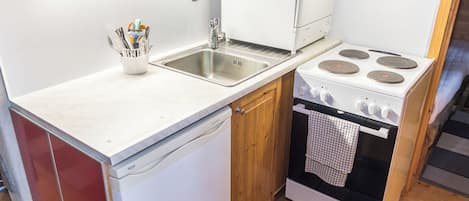 A compact kitchen with a sink, stove, and wooden cabinets.