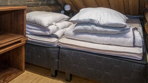 Une chambre confortable dans un chalet en rondins, avec deux lits, une table de chevet en bois et une petite lampe.
