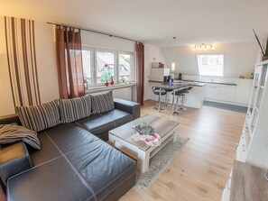 Una sala de estar moderna con un sofá, una mesa de centro y una zona de cocina con un taburete de bar.