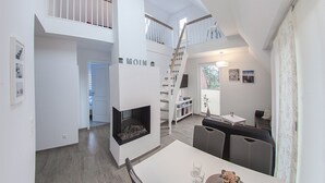 Et moderne interiør med pejs, spiseplads og trappe op til et loft.