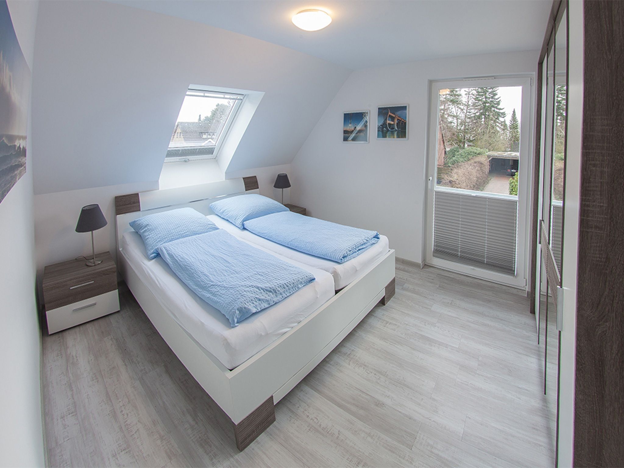 Ein Schlafzimmer mit Oberlicht, einem Bett mit zwei Kissen, einem Nachttisch und einem Fenster.