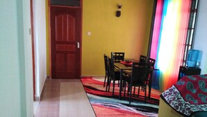 Un coin repas comprenant une table et des chaises, un ventilateur de plafond et un habillage de fenêtre aux couleurs vives.