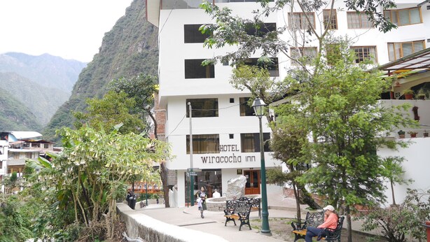 A hotel with multiple floors, outdoor seating, and a mountainous backdrop. - Hotel Wiracocha Inn (Machu Picchu)