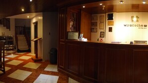 A reception area with a wooden counter, a reception desk, and a wall with various plaques and certificates. - Hotel Wiracocha Inn (Machu Picchu)