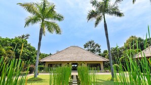 A building with a thatched roof, surrounded by lush greenery and palm trees. - Villa Lotus - Let The Sea Set You Free (Seririt)