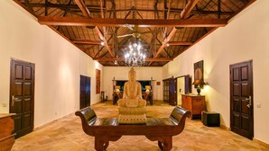 A spacious room with a high ceiling, a large Buddha statue, and a chandelier. - Villa Lotus - Let The Sea Set You Free (Seririt)