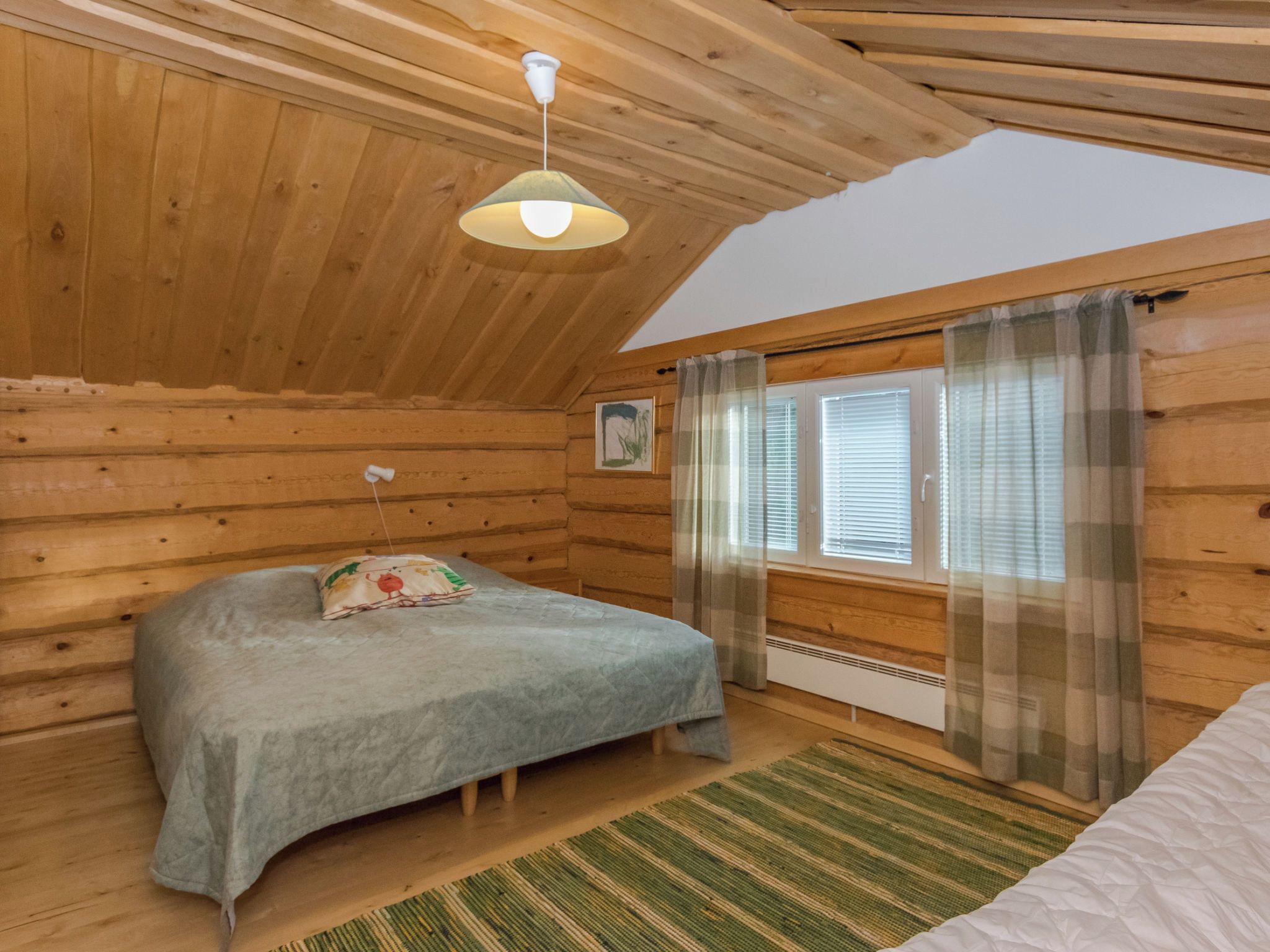 Une chambre confortable avec un lit, une fenêtre avec des rideaux, un radiateur et un luminaire au plafond.