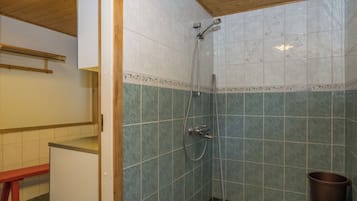 Une salle de bain avec une douche, un banc et une poubelle.