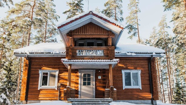 A wooden cabin with a balcony, surrounded by snow-covered trees. - Tainan tupa by Interhome (Sysmä)