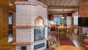 A cozy cabin interior with a fireplace, wooden walls, a dining area, and a television. - Tainan tupa by Interhome (Sysmä)