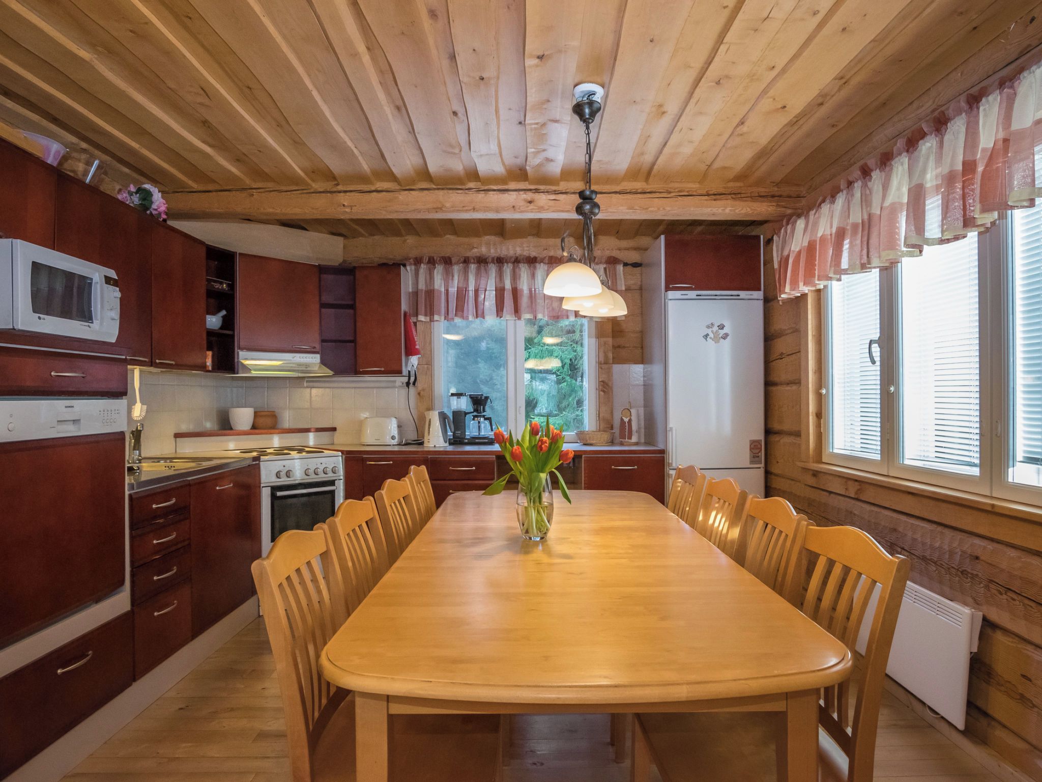 Un interior de madera con una mesa de comedor, sillas, una cocina con electrodomésticos y una ventana con persianas.