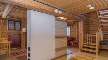 Un intérieur en bois avec un mur blanc, un escalier en bois et une chaise rouge.