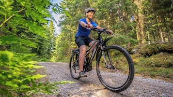 A person riding a mountain bike on a gravel path surrounded by dense forest.
