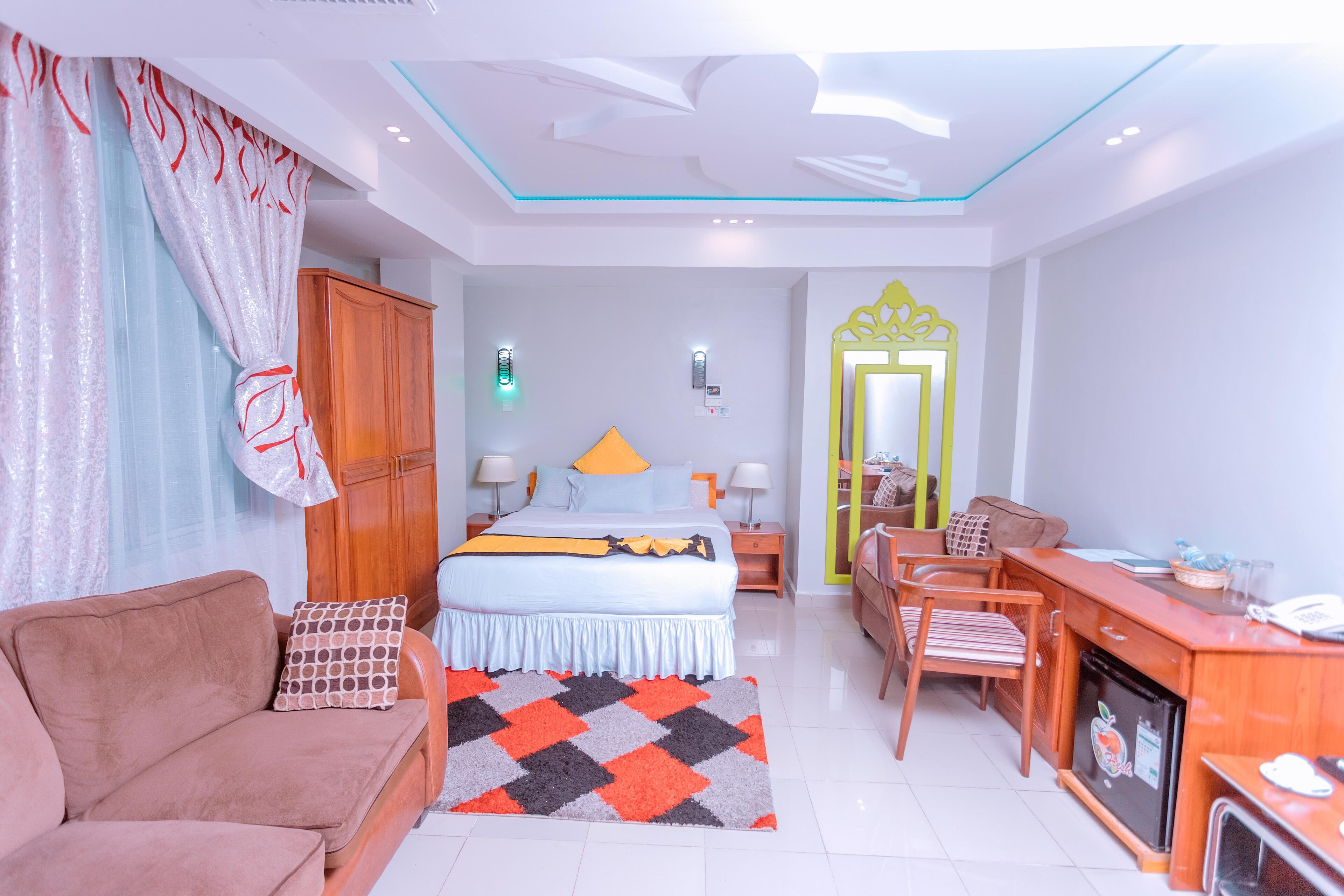 A hotel room with a bed, a sofa, a desk, and a minibar.