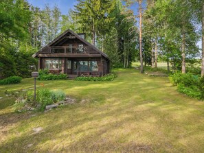 A wooden cabin with a porch, surrounded by a well-maintained lawn and dense trees. - Uimaranta by Interhome (Pieksämäki)