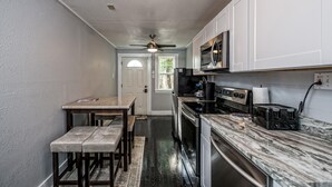 A compact kitchen with white cabinets, a microwave, a stove, and a toaster.