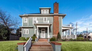 A two-story house with a front porch, a brick chimney, and a well-maintained lawn.