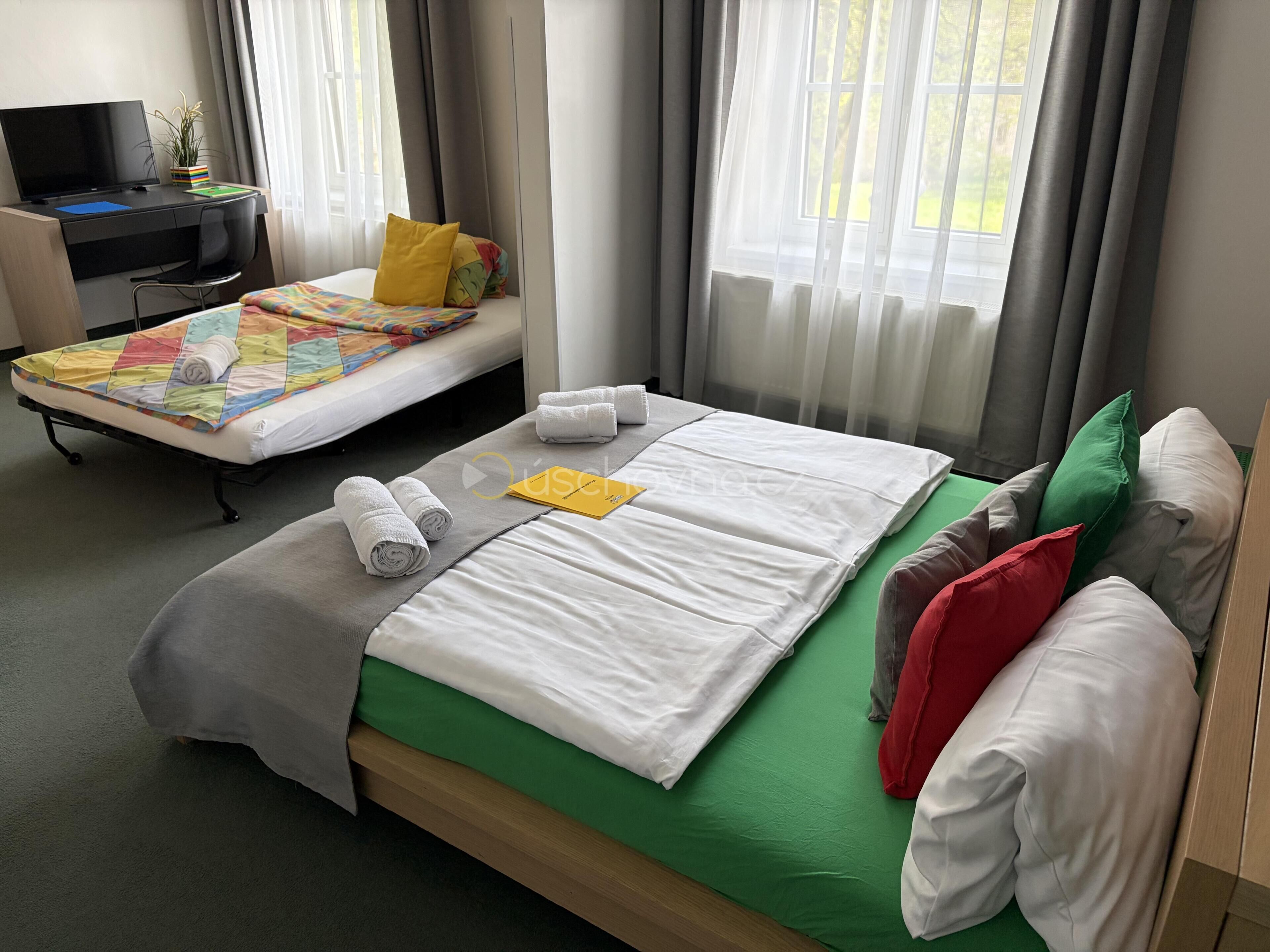 Et hotelværelse med seng, skrivebord og fjernsyn.