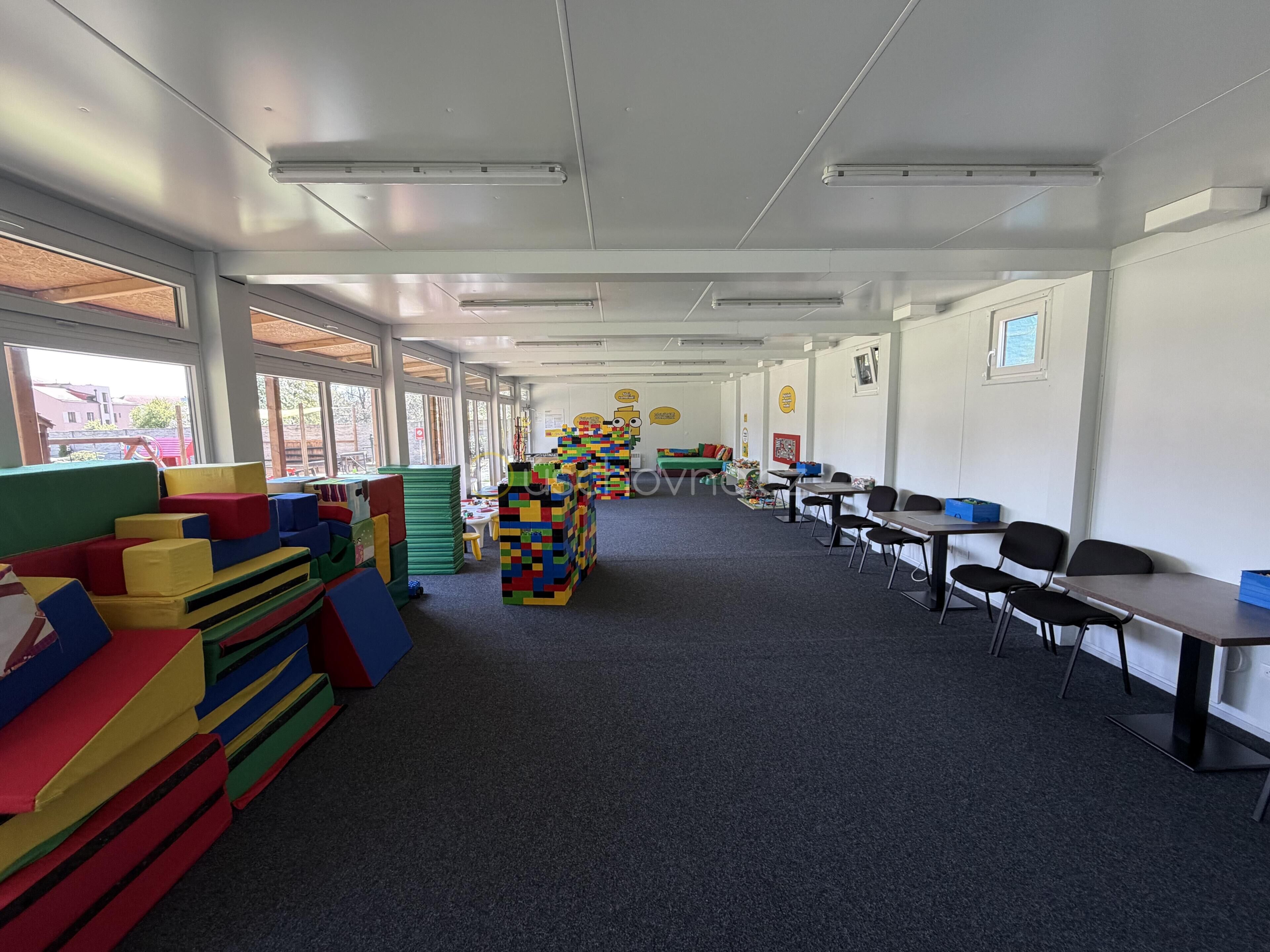 A classroom with colorful play structures, tables, and chairs arranged for learning activities.