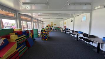 Un aula con estructuras lúdicas coloridas, mesas y sillas dispuestas para actividades de aprendizaje.