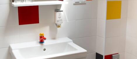 A bathroom with a white sink, a mirror, a small toy, and colorful tiles on the walls.