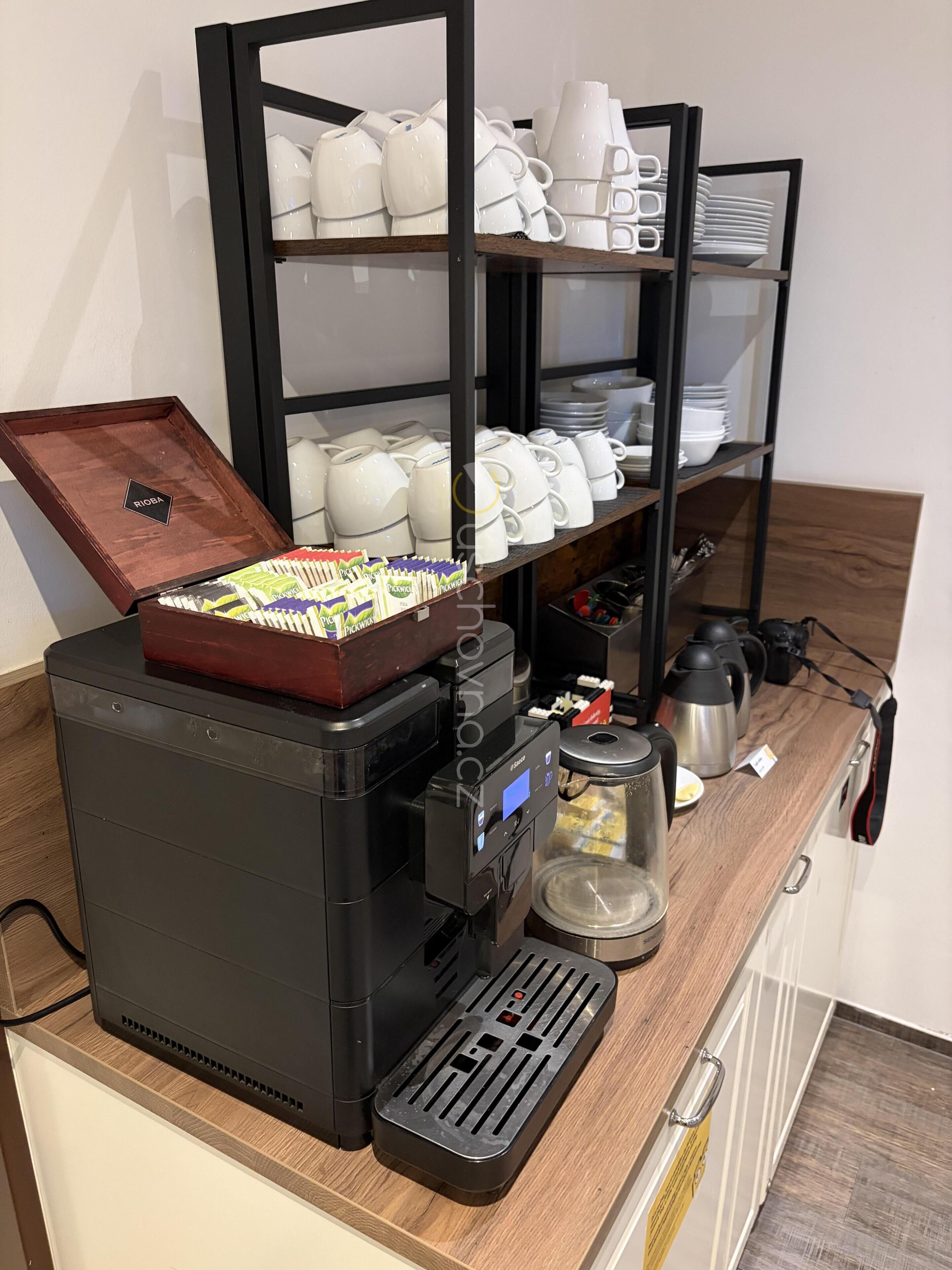 Una cafetera con una bandeja de pasteles, una tetera y una jarra de café sobre una encimera de madera.
