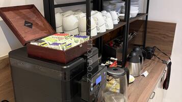 Una cafetera con una bandeja de pasteles, una tetera y una jarra de café sobre una encimera de madera.
