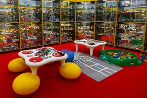 A toy store with multiple shelves filled with toys, a play area with a ball pit, and a table with toys.