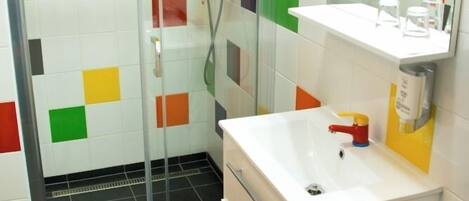 Un baño con ducha, lavamanos y espejo.