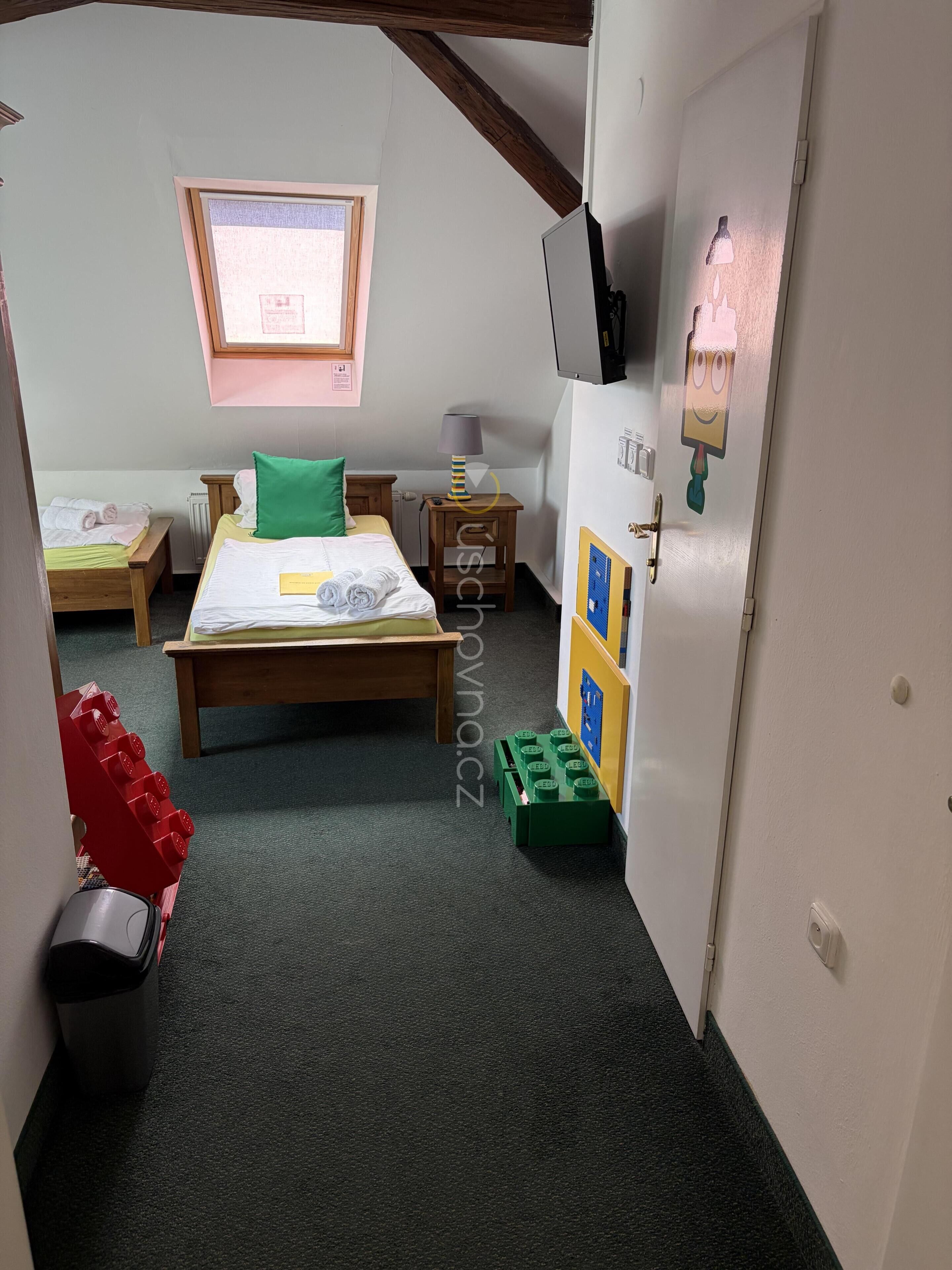 Una habitación con dos camas, una ventana, un radiador, una lámpara y una puerta con un adorno en la pared.